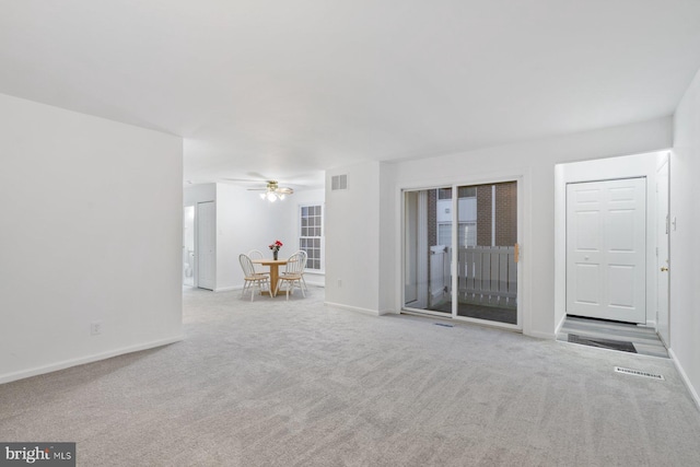 unfurnished living room featuring light carpet and ceiling fan