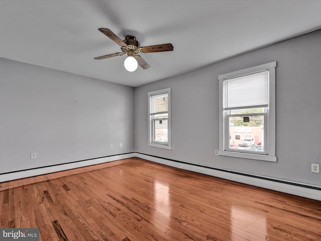 empty room featuring a baseboard radiator, plenty of natural light, hardwood / wood-style floors, and ceiling fan