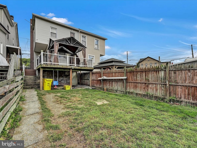 rear view of property featuring a yard and a wooden deck