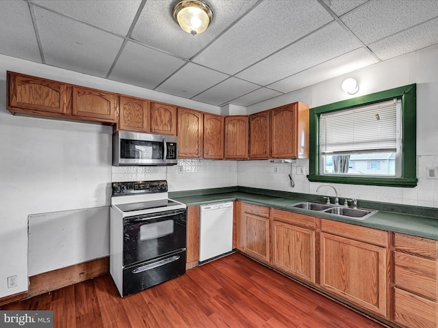 kitchen featuring tasteful backsplash, a drop ceiling, white appliances, sink, and dark hardwood / wood-style flooring