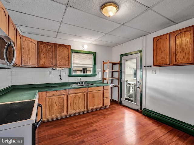 kitchen with tasteful backsplash, dark wood-type flooring, a paneled ceiling, electric range, and sink