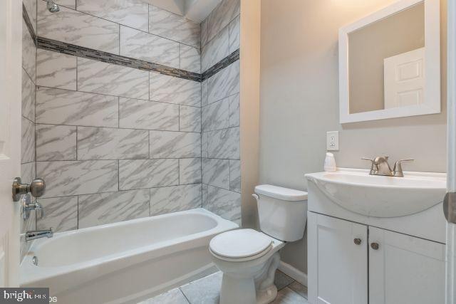 full bathroom featuring vanity, tiled shower / bath combo, toilet, and tile patterned flooring