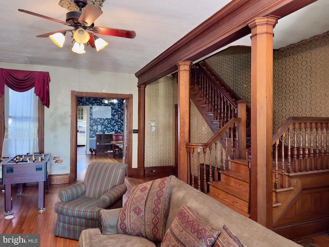 living room featuring hardwood / wood-style floors, ornate columns, and ceiling fan