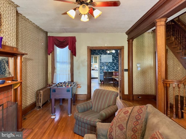 living room featuring ornate columns, hardwood / wood-style flooring, radiator heating unit, and ceiling fan