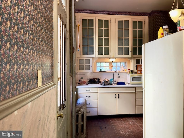 kitchen featuring white appliances, white cabinetry, dark tile patterned floors, and hanging light fixtures