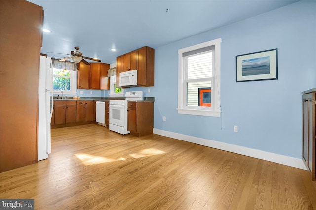 kitchen featuring ceiling fan, white appliances, sink, and light hardwood / wood-style flooring