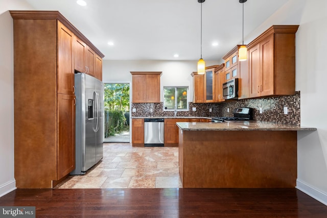 kitchen featuring kitchen peninsula, tasteful backsplash, decorative light fixtures, stainless steel appliances, and dark stone counters