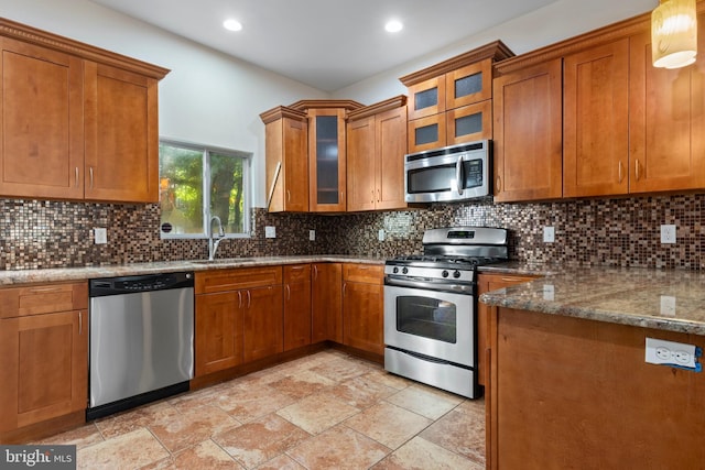 kitchen with stainless steel appliances, backsplash, stone counters, and sink