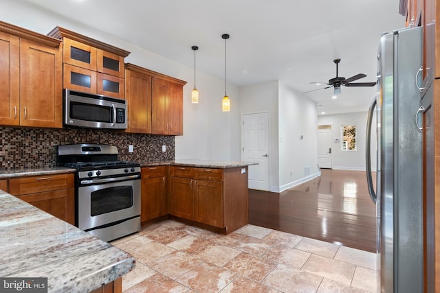 kitchen with light hardwood / wood-style floors, decorative backsplash, pendant lighting, stainless steel appliances, and kitchen peninsula