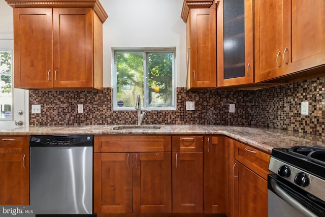 kitchen with light stone countertops, sink, stainless steel appliances, and backsplash