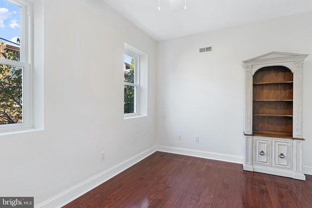 unfurnished living room featuring plenty of natural light and dark hardwood / wood-style floors