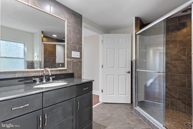 bathroom featuring tile patterned flooring, a shower with shower door, vanity, and tile walls