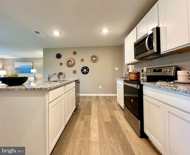 kitchen featuring light stone countertops, stainless steel appliances, sink, white cabinetry, and light hardwood / wood-style flooring