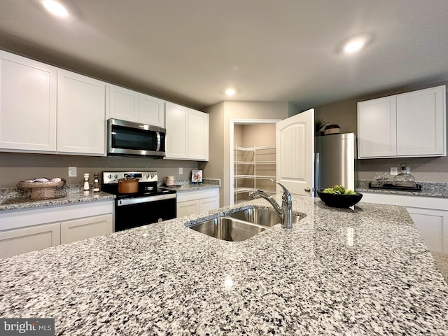 kitchen featuring light stone counters, white cabinetry, sink, and stainless steel appliances