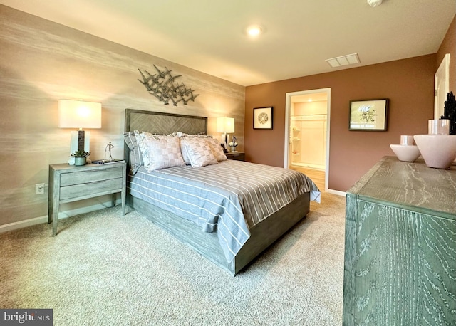 bedroom with ensuite bathroom and carpet floors