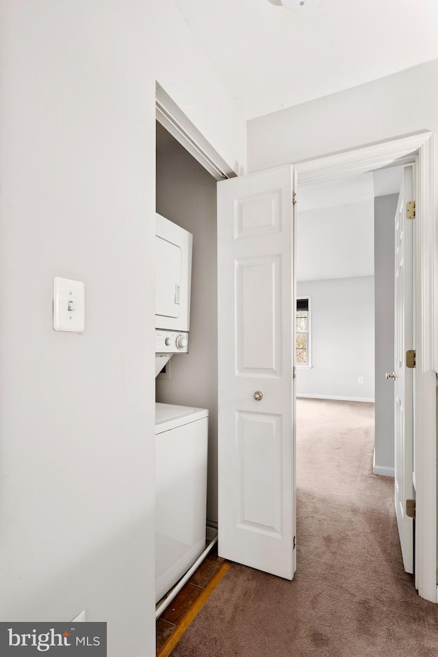 laundry room featuring stacked washer and clothes dryer and dark colored carpet