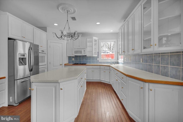 kitchen featuring stainless steel fridge with ice dispenser, white cabinetry, hanging light fixtures, and a center island