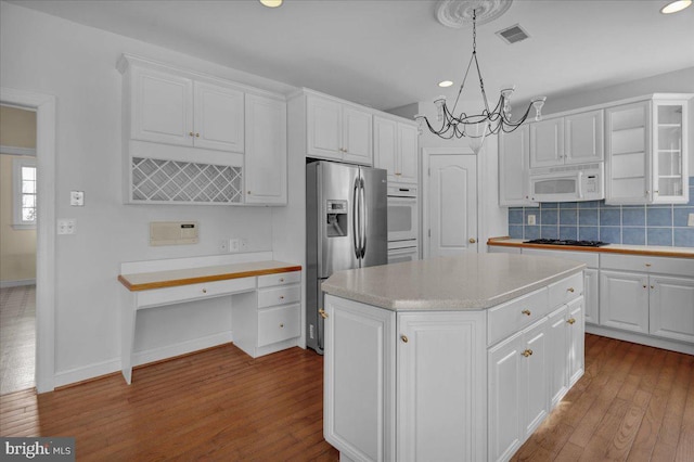 kitchen featuring stainless steel refrigerator with ice dispenser, white cabinetry, decorative light fixtures, and a center island