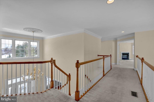 hall with light colored carpet, a notable chandelier, and ornamental molding