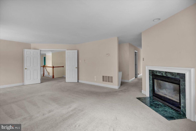 unfurnished living room with light colored carpet and a high end fireplace