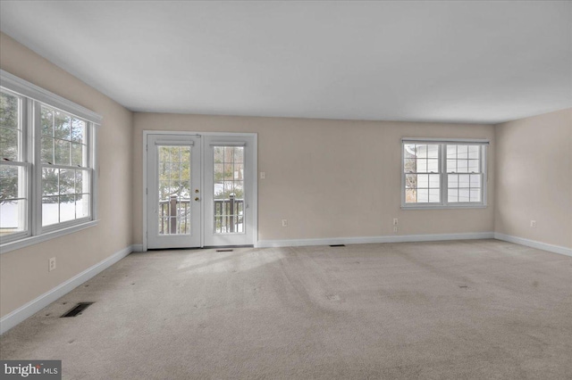 carpeted spare room with a healthy amount of sunlight and french doors