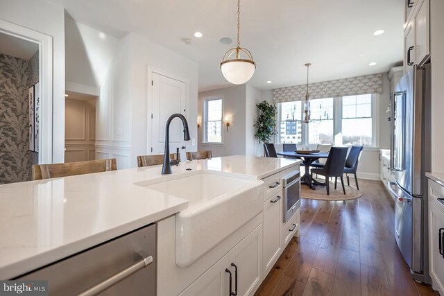 kitchen with decorative light fixtures, sink, dark hardwood / wood-style floors, white cabinets, and appliances with stainless steel finishes