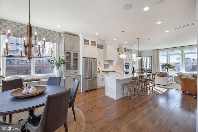 kitchen with dark hardwood / wood-style flooring, hanging light fixtures, white cabinets, appliances with stainless steel finishes, and a center island