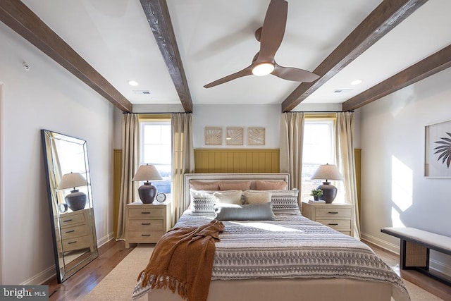 bedroom featuring beamed ceiling, hardwood / wood-style flooring, multiple windows, and ceiling fan