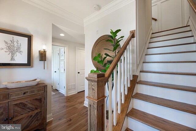 staircase with wood-type flooring and crown molding