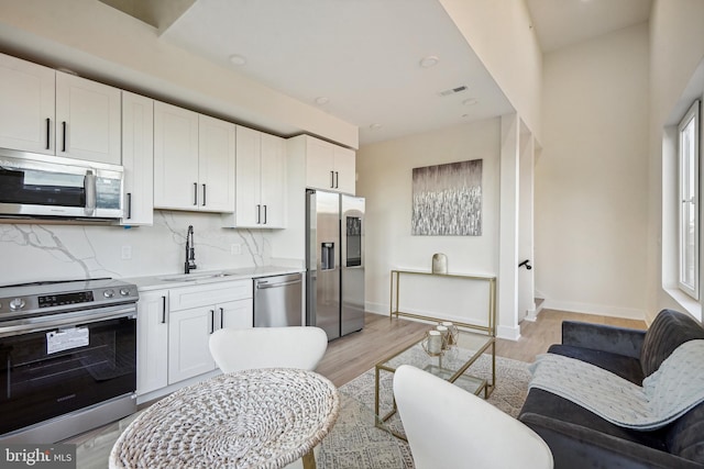 kitchen with white cabinets, appliances with stainless steel finishes, plenty of natural light, and sink