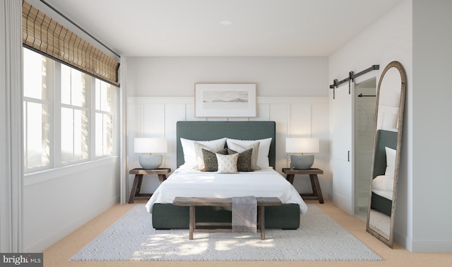 bedroom featuring a barn door and light colored carpet