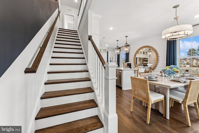 staircase featuring hardwood / wood-style flooring and a notable chandelier