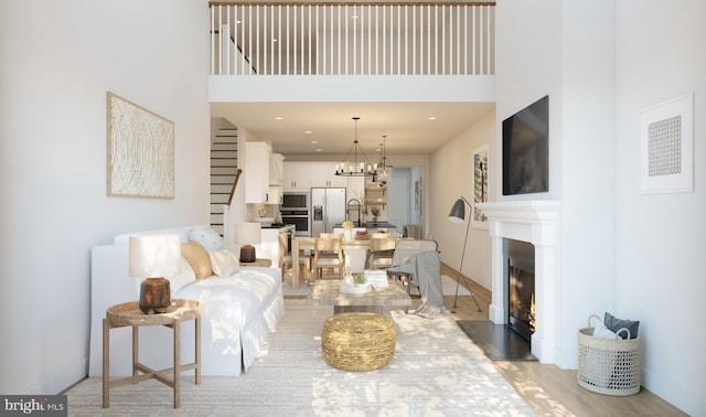 living room featuring a high ceiling, light hardwood / wood-style floors, a notable chandelier, and sink