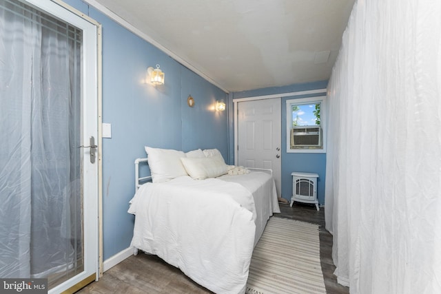 bedroom with hardwood / wood-style flooring, a wood stove, cooling unit, and crown molding