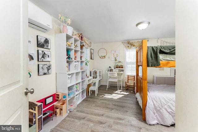 bedroom with light wood-type flooring and a wall unit AC