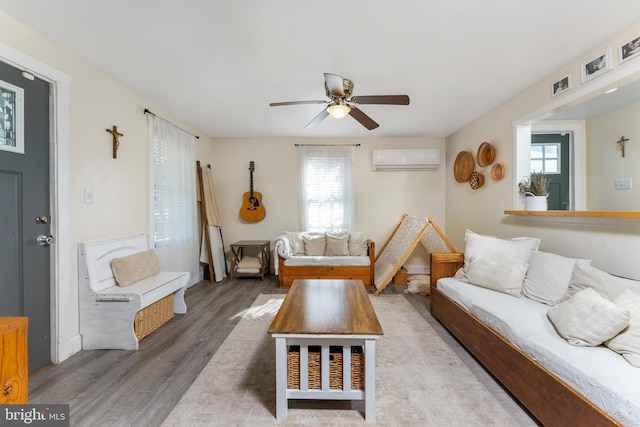 living room with a wall mounted AC, hardwood / wood-style flooring, a wealth of natural light, and ceiling fan