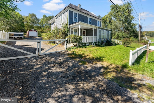 view of front of home featuring a porch, a garage, an outdoor structure, and a front yard