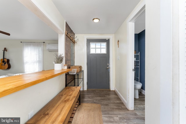 foyer entrance with a wall mounted AC, a healthy amount of sunlight, and hardwood / wood-style flooring