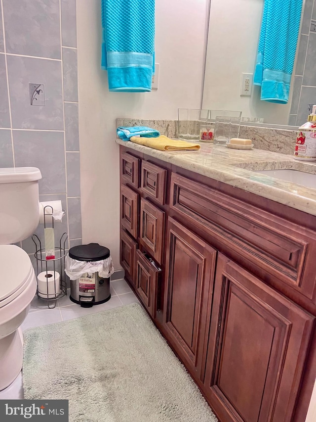 bathroom featuring vanity, toilet, tile patterned floors, and tile walls