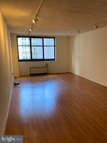 unfurnished room with hardwood / wood-style flooring, a healthy amount of sunlight, a textured ceiling, and track lighting