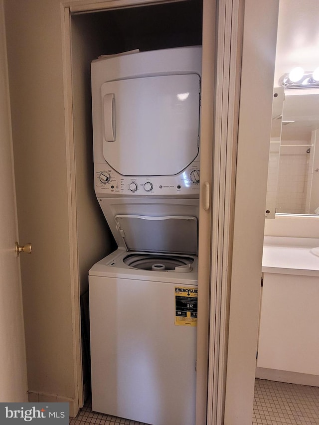 laundry area with light tile patterned floors and stacked washing maching and dryer