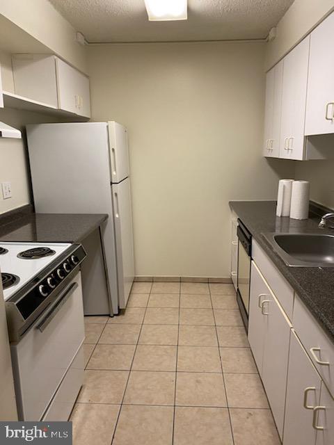 kitchen with white electric range oven, dishwashing machine, sink, light tile patterned floors, and white cabinetry