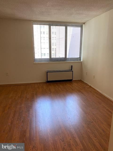 unfurnished room with radiator, a textured ceiling, and hardwood / wood-style flooring