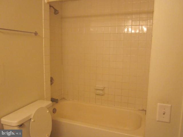 bathroom with tiled shower / bath combo and toilet