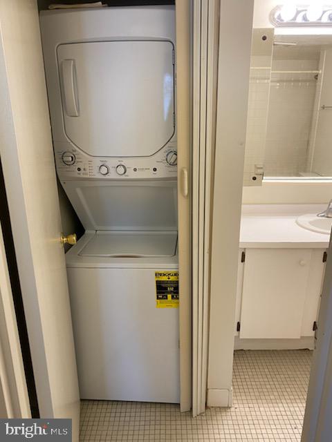 laundry area featuring stacked washer and clothes dryer and sink