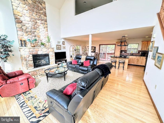 living room with a fireplace, light hardwood / wood-style flooring, and high vaulted ceiling