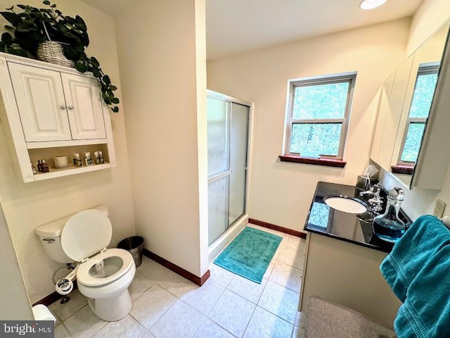 bathroom with tile patterned floors, vanity, a shower with shower door, and toilet