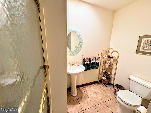 bathroom with toilet, tile patterned floors, and a shower with shower door