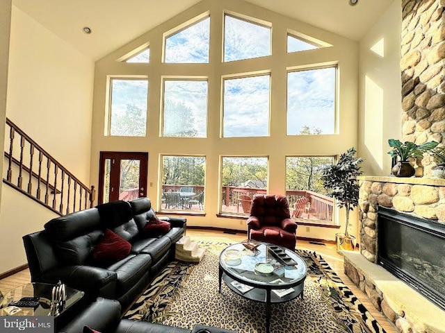 living room with a stone fireplace, a wealth of natural light, and high vaulted ceiling