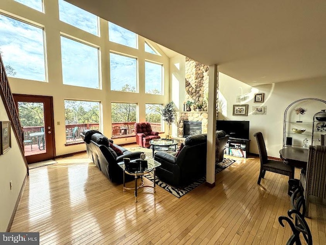 living room with a fireplace, light hardwood / wood-style flooring, and a high ceiling